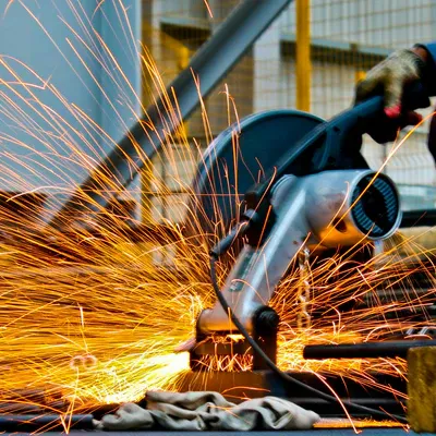 A Table saw cutting a pipe and sparks flying