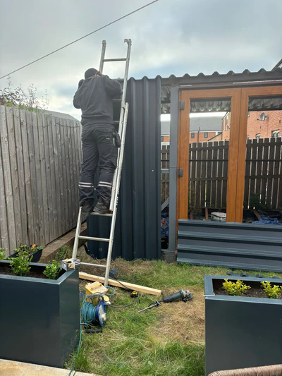 A garden shed  with a man up a ladder