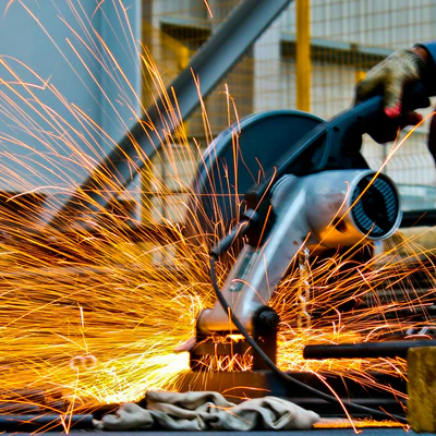 A Table saw cutting a pipe and sparks flying