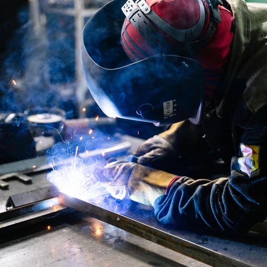 A man welding whilst wearing protective headwear